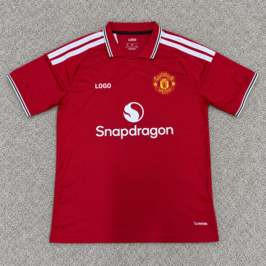 Manchester United · Local 26/27 · Fan · Escudo conservado y LOGO · Alfombra gris
